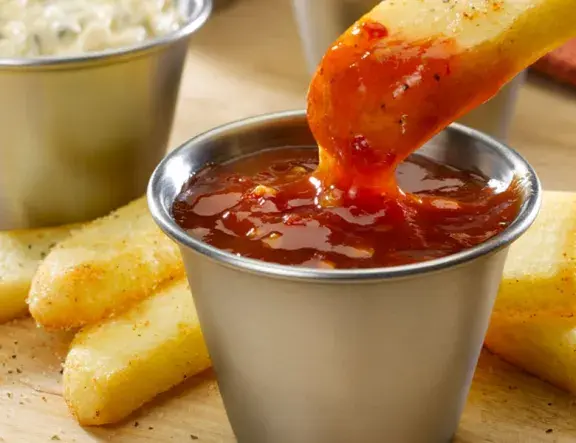 Steak Fry dipping into spicy sauce
